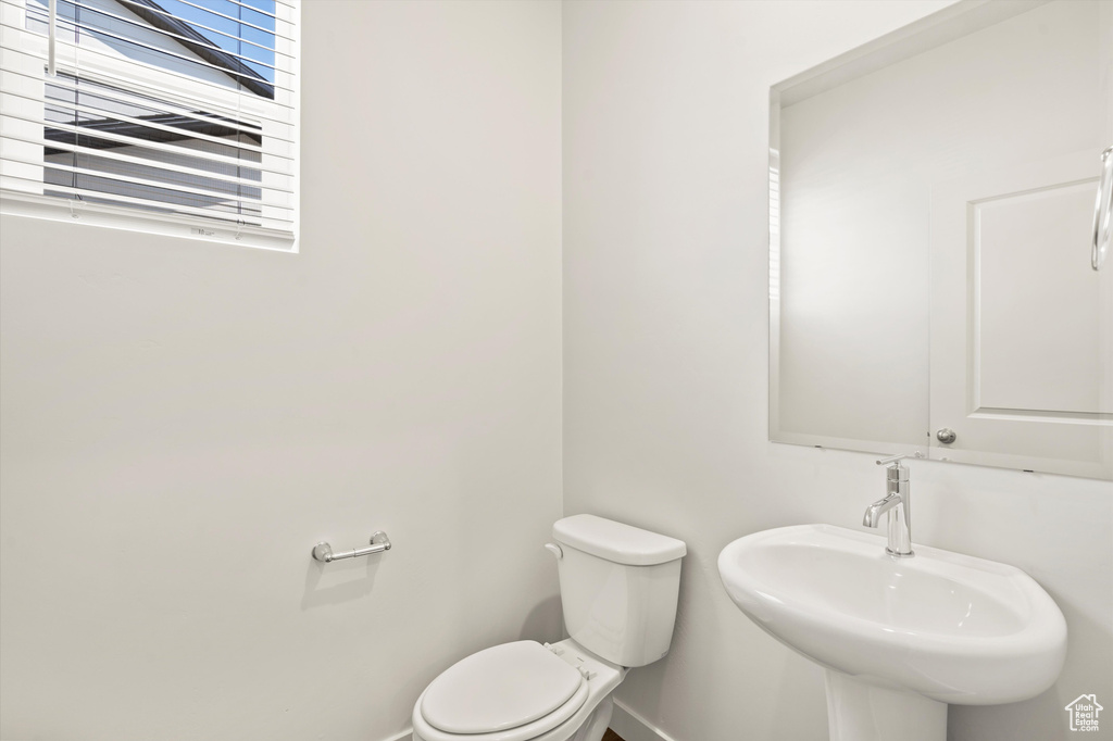 Half bath featuring baseboards, toilet, and a sink