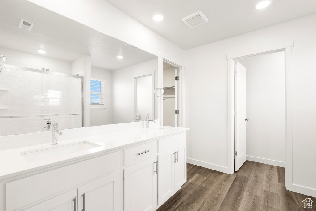 Full bathroom featuring wood finished floors, double vanity, a stall shower, recessed lighting, and baseboards
