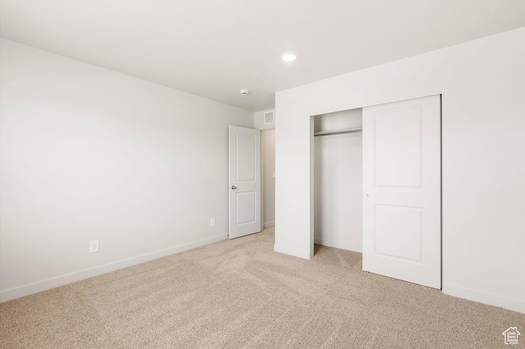 Unfurnished bedroom featuring light carpet, a closet, baseboards, and recessed lighting