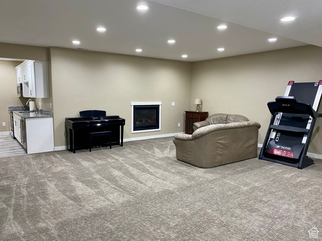 Living area featuring a glass covered fireplace, baseboards, recessed lighting, and light colored carpet
