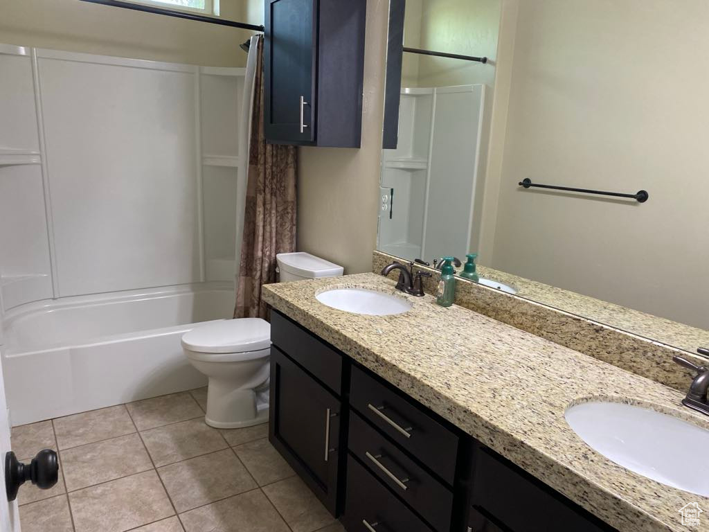 Full bathroom featuring a sink, shower / bathtub combination with curtain, toilet, and double vanity