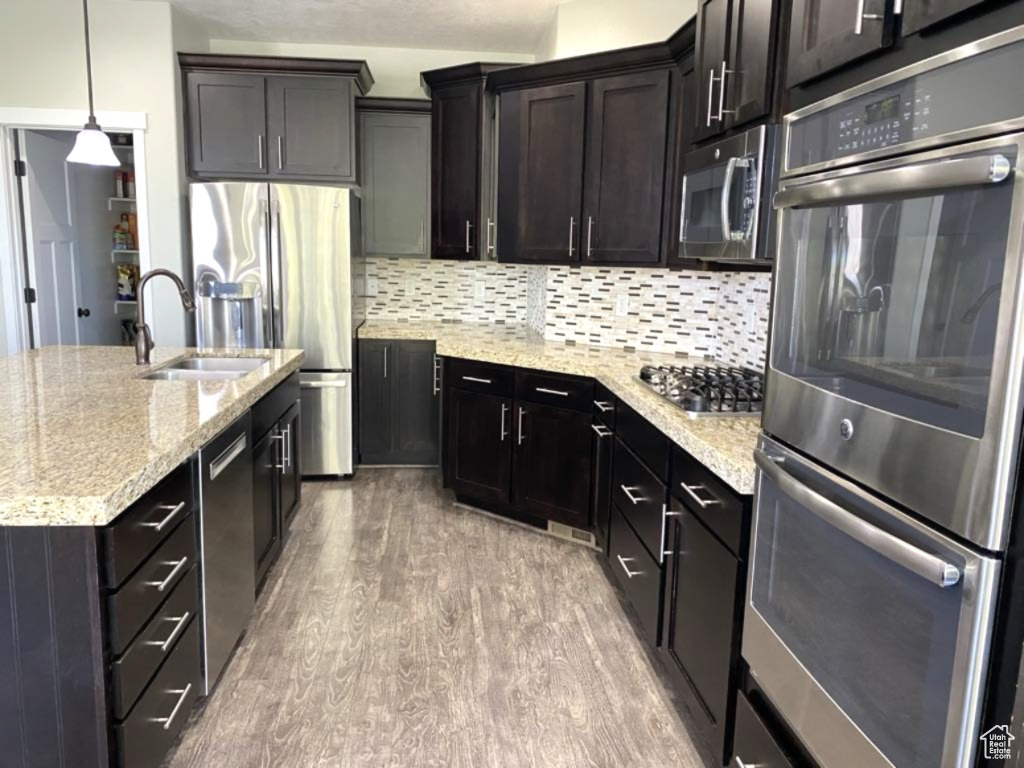 Kitchen featuring a sink, appliances with stainless steel finishes, tasteful backsplash, and wood finished floors