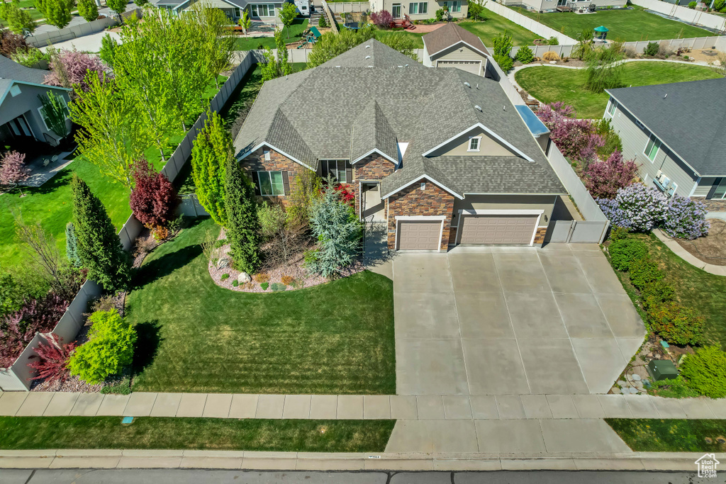 View of front of home with stone siding, a shingled roof, an attached garage, driveway, and a residential view