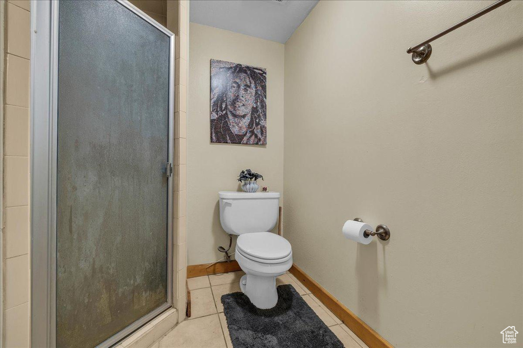 Bathroom featuring tile patterned flooring, a shower stall, and toilet