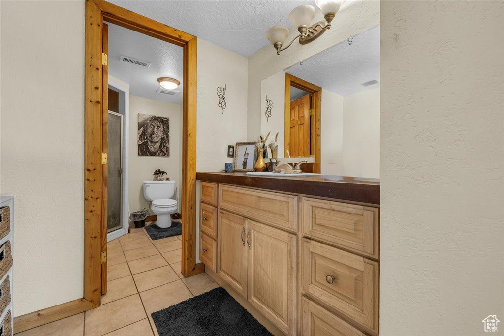 Full bath with vanity, toilet, tile patterned floors, visible vents, and a stall shower