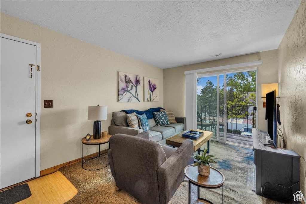 Living area with baseboards, a textured ceiling, a textured wall, and wood finished floors