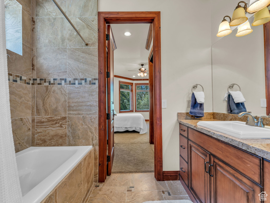 Ensuite bathroom featuring vanity, ensuite bath, a ceiling fan, baseboards, and tiled shower / bath combo