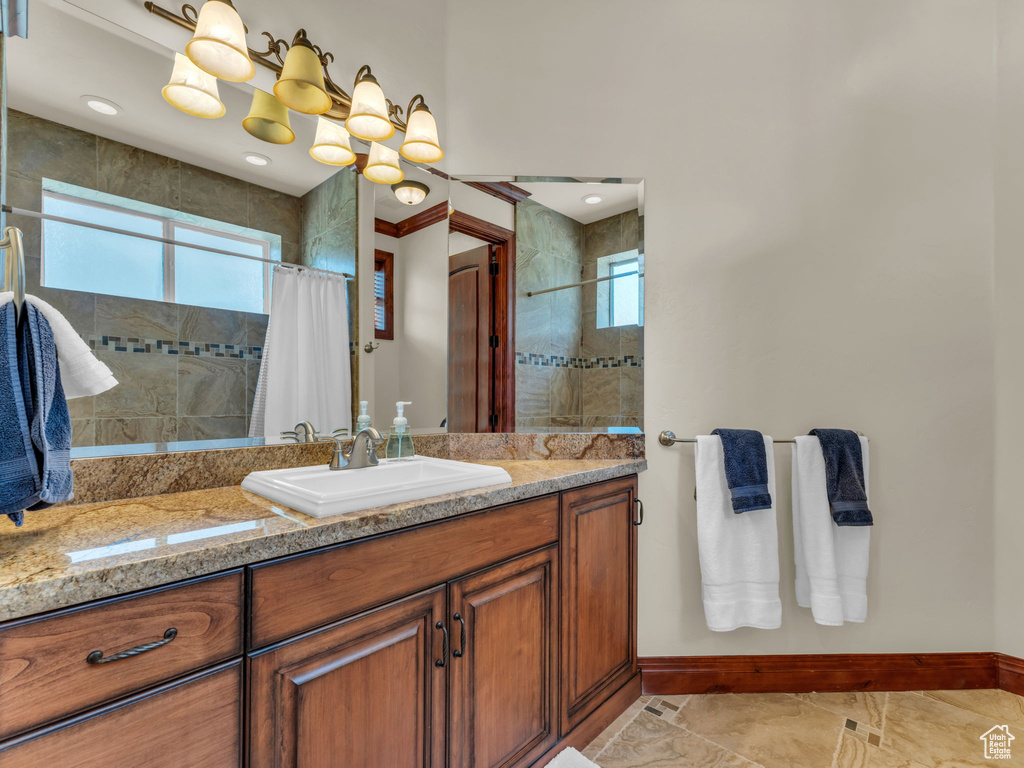 Bathroom featuring baseboards, vanity, and tiled shower