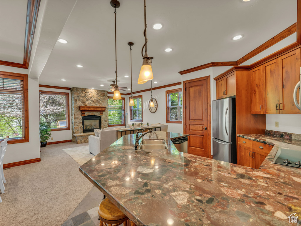Kitchen with brown cabinetry, crown molding, a sink, freestanding refrigerator, and light carpet