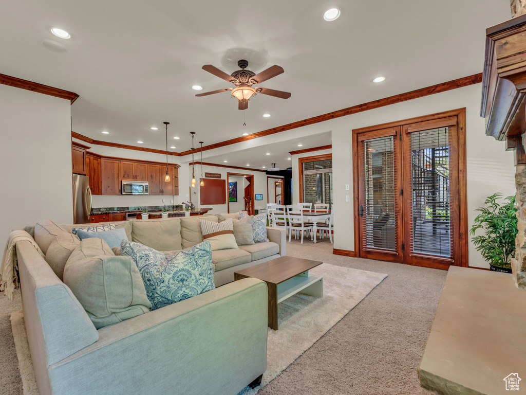 Living room with ornamental molding, recessed lighting, light colored carpet, french doors, and a ceiling fan