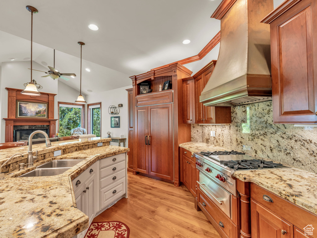 Kitchen featuring a ceiling fan, stainless steel gas cooktop, light wood-type flooring, a sink, and custom range hood