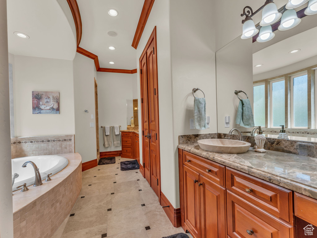 Bathroom with a garden tub, crown molding, vanity, baseboards, and recessed lighting