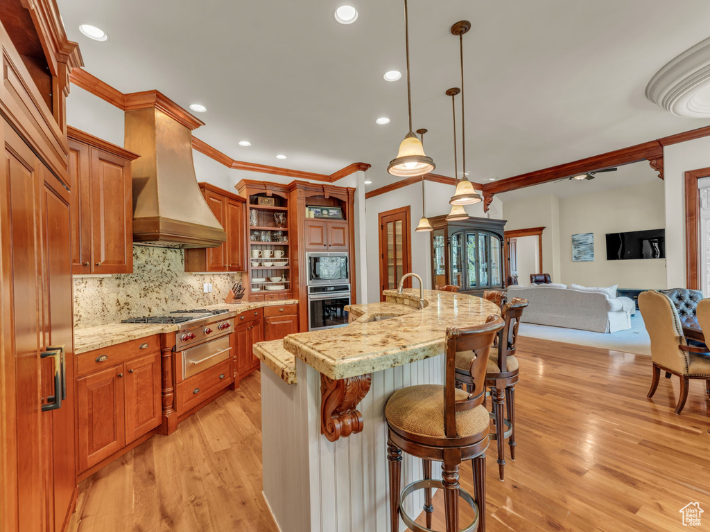 Kitchen with crown molding, appliances with stainless steel finishes, open shelves, a sink, and custom exhaust hood