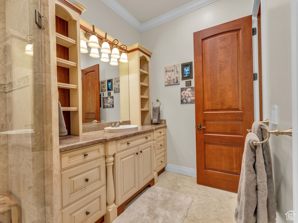 Bathroom featuring tile patterned flooring, vanity, baseboards, an enclosed shower, and ornamental molding