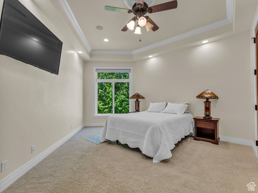 Bedroom with light colored carpet, a raised ceiling, recessed lighting, baseboards, and ornamental molding