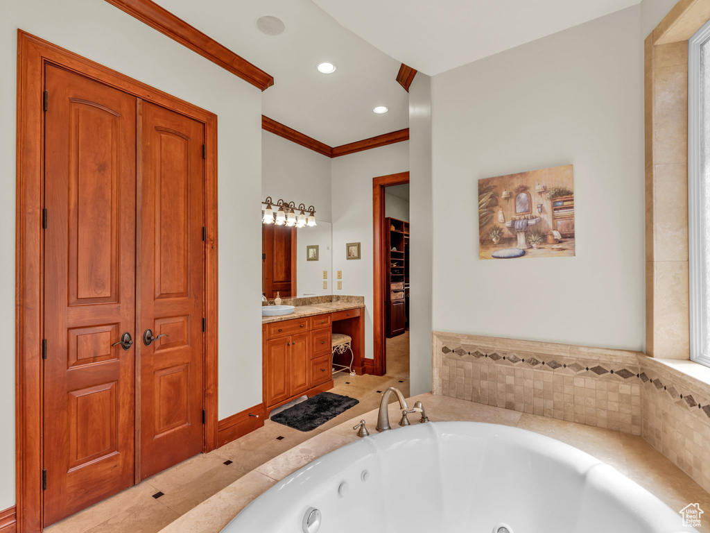 Full bathroom with recessed lighting, vanity, ornamental molding, and a tub with jets