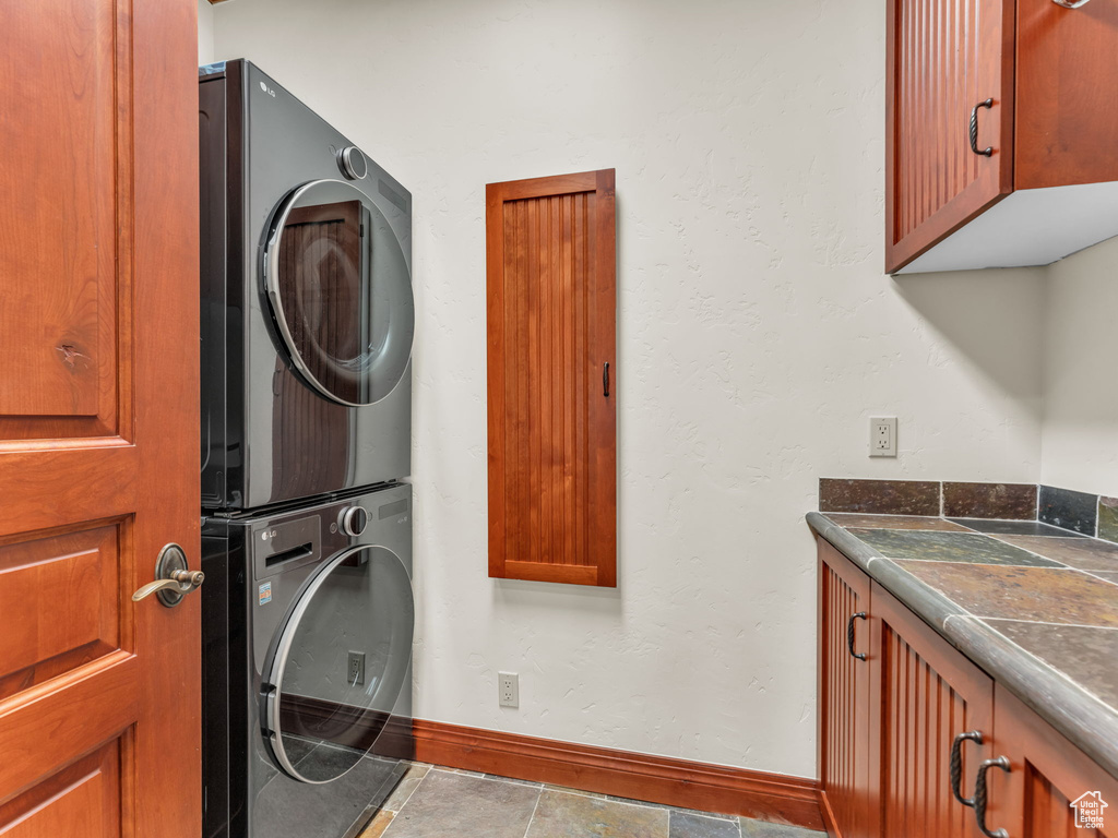 Laundry area featuring cabinet space, baseboards, and stacked washer and clothes dryer