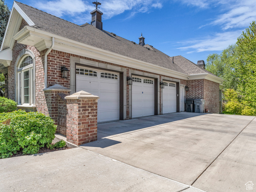 View of home\'s exterior featuring brick siding, a chimney, and concrete driveway