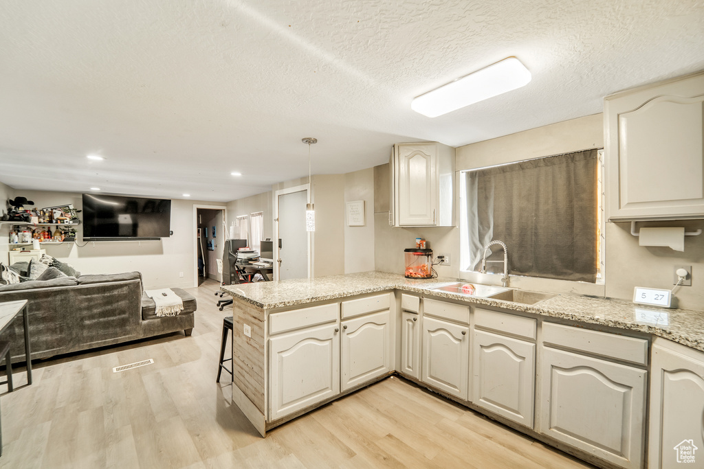 Kitchen with light wood-type flooring, a sink, a peninsula, and open floor plan