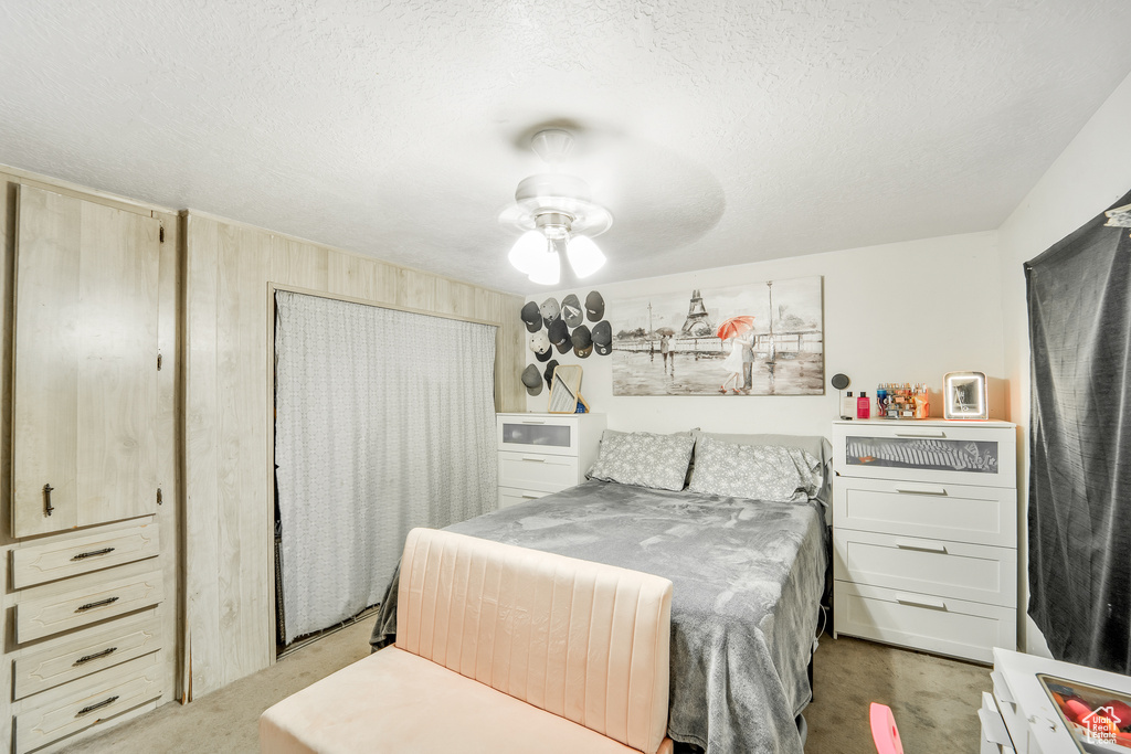 Bedroom featuring a textured ceiling, light colored carpet, and ceiling fan
