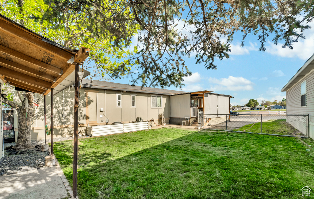 Back of property featuring a lawn, a gate, and fence