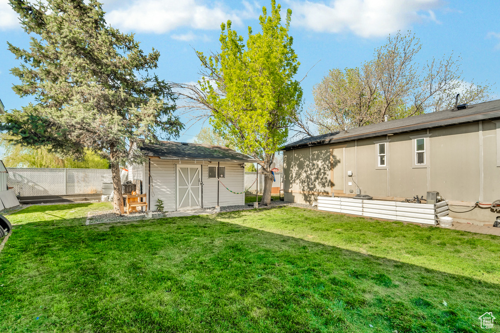 View of yard with an outdoor structure, a fenced backyard, and a storage shed