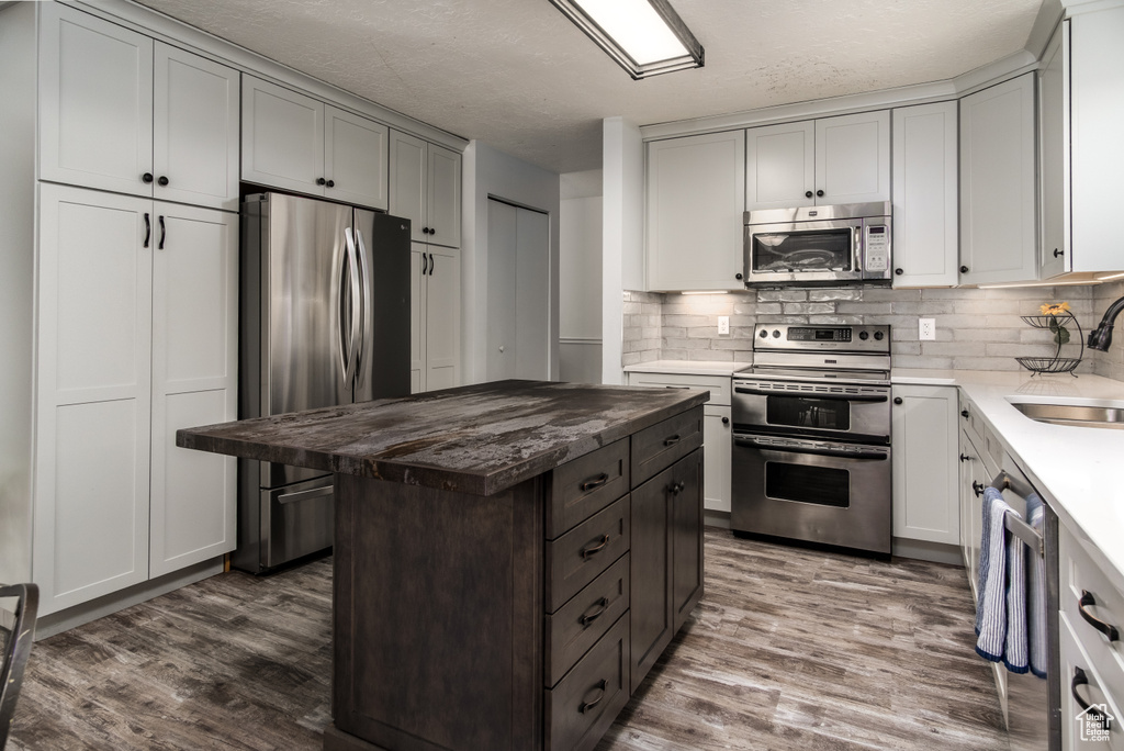 Kitchen featuring backsplash, stainless steel appliances, dark wood-style floors, and a sink