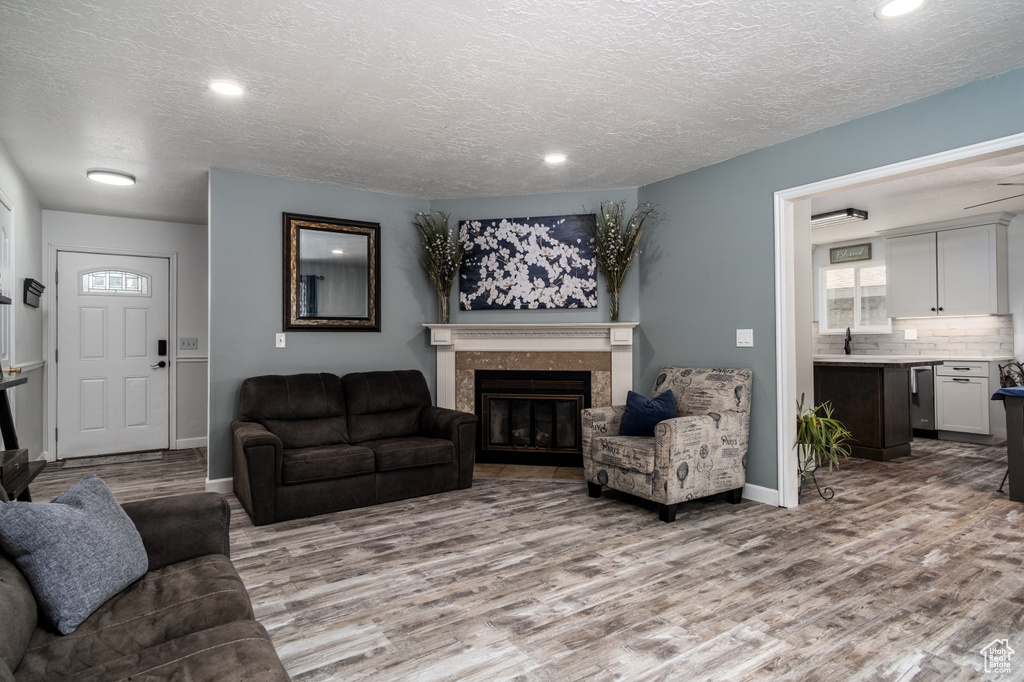Living room with wood finished floors, a fireplace, baseboards, recessed lighting, and a textured ceiling