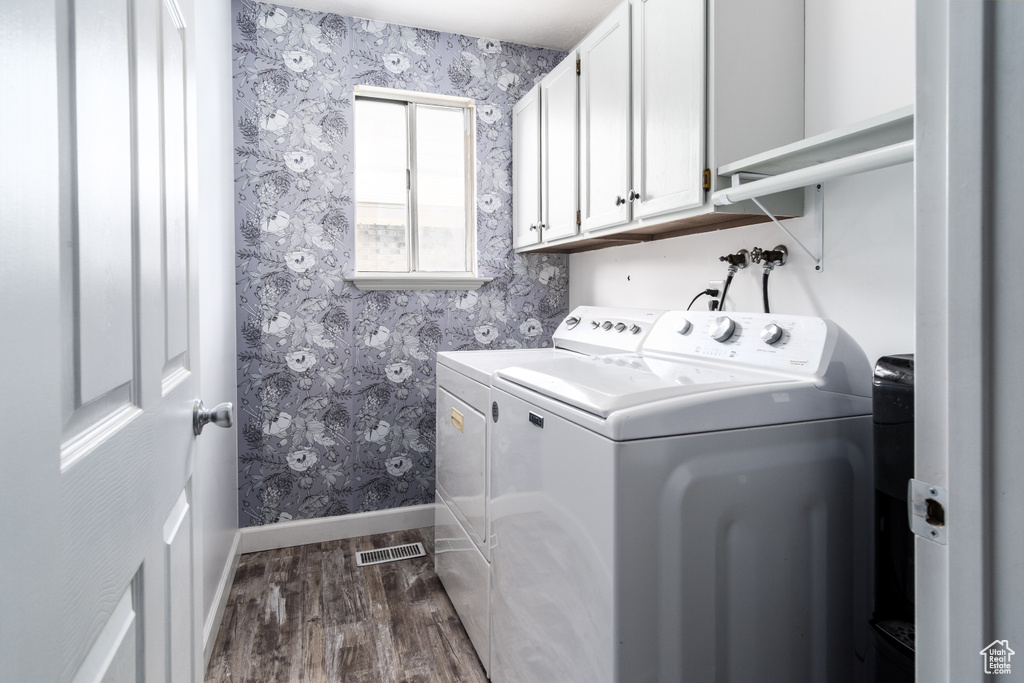Laundry area with washing machine and clothes dryer, cabinet space, baseboards, wallpapered walls, and dark wood-style floors