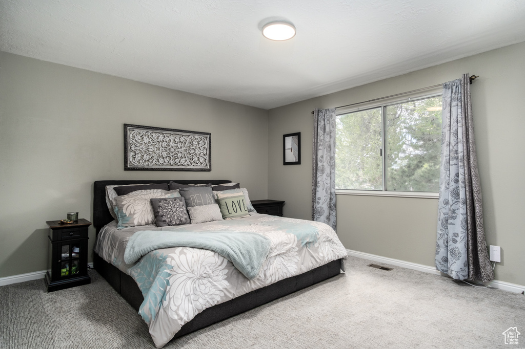 Carpeted bedroom featuring baseboards and visible vents