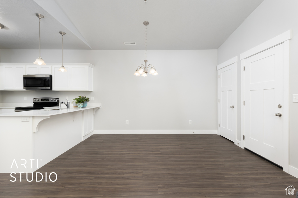 Kitchen with a breakfast bar area, light countertops, dark wood finished floors, stainless steel appliances, and baseboards