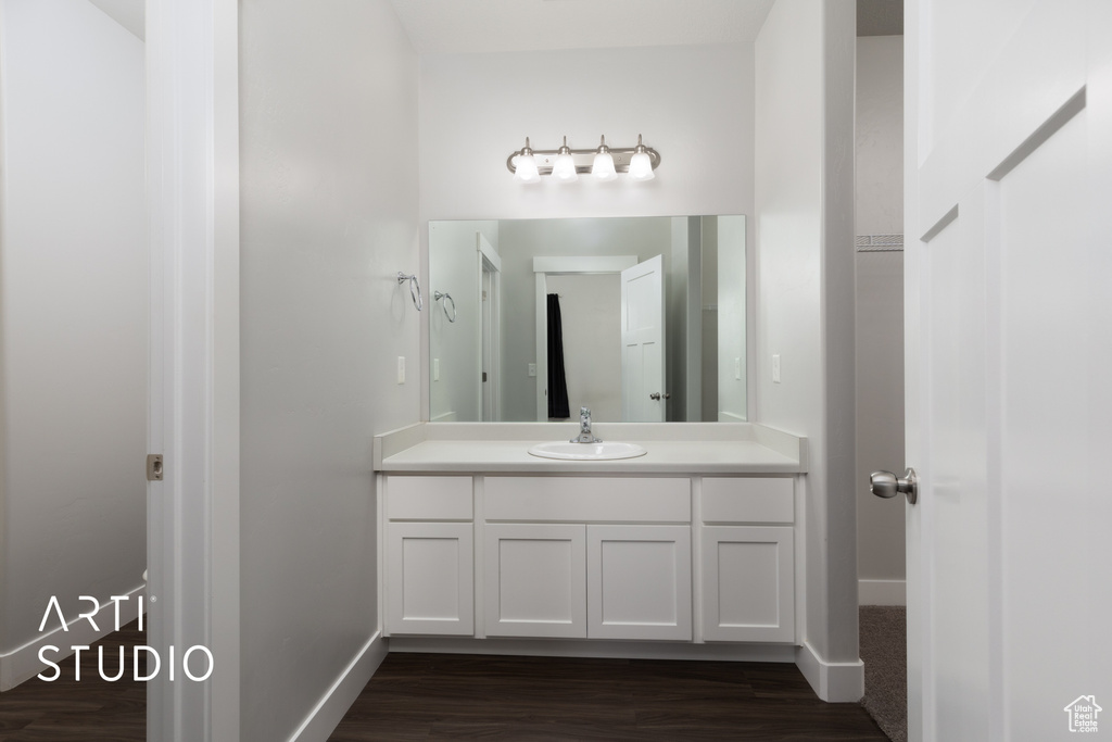 Bathroom featuring baseboards, wood finished floors, and vanity
