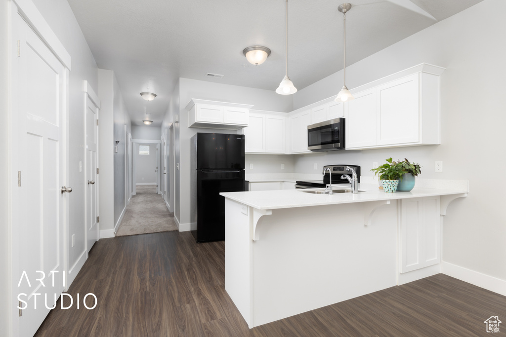 Kitchen with light countertops, stainless steel appliances, a sink, and a peninsula
