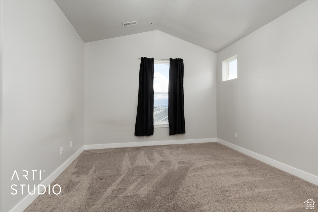 Unfurnished room with visible vents, baseboards, carpet, and lofted ceiling