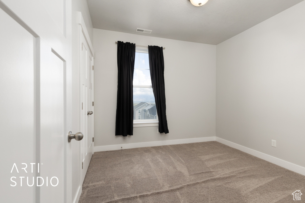 Carpeted empty room featuring baseboards and visible vents