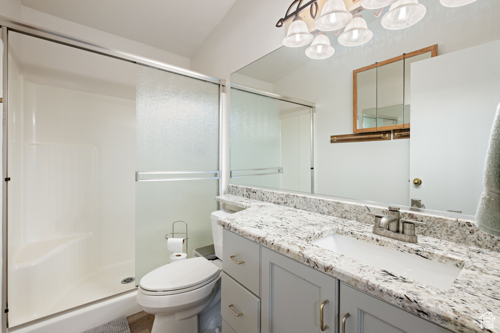 Full bathroom featuring vanity, toilet, an inviting chandelier, and a stall shower