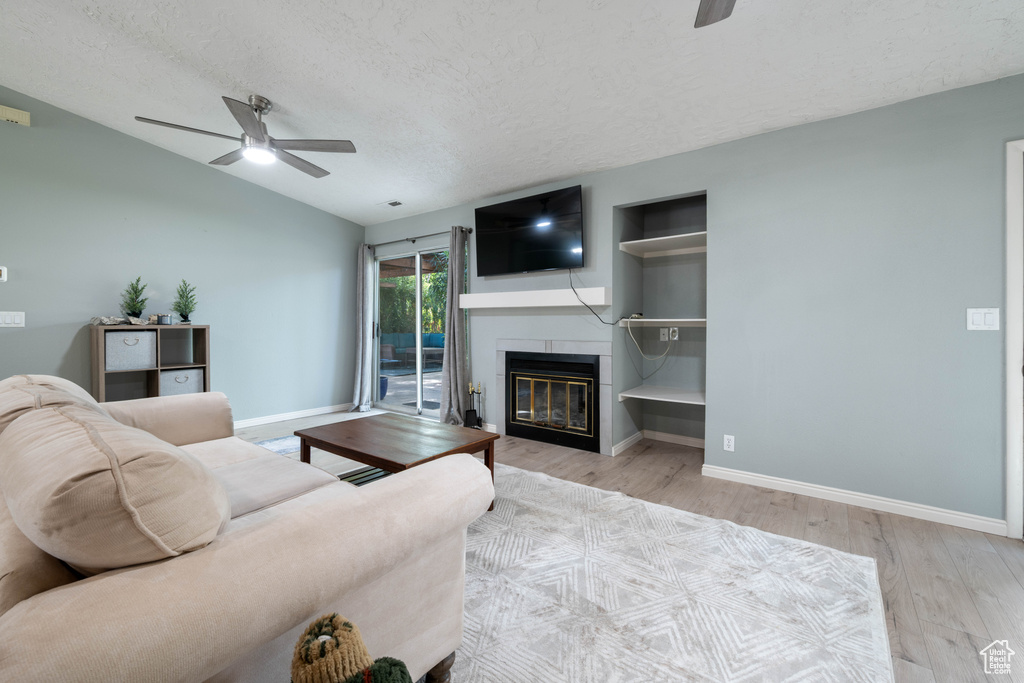 Living area featuring baseboards, a ceiling fan, a textured ceiling, and wood finished floors