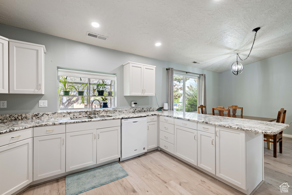 Kitchen with a peninsula, light wood-type flooring, a sink, and dishwasher