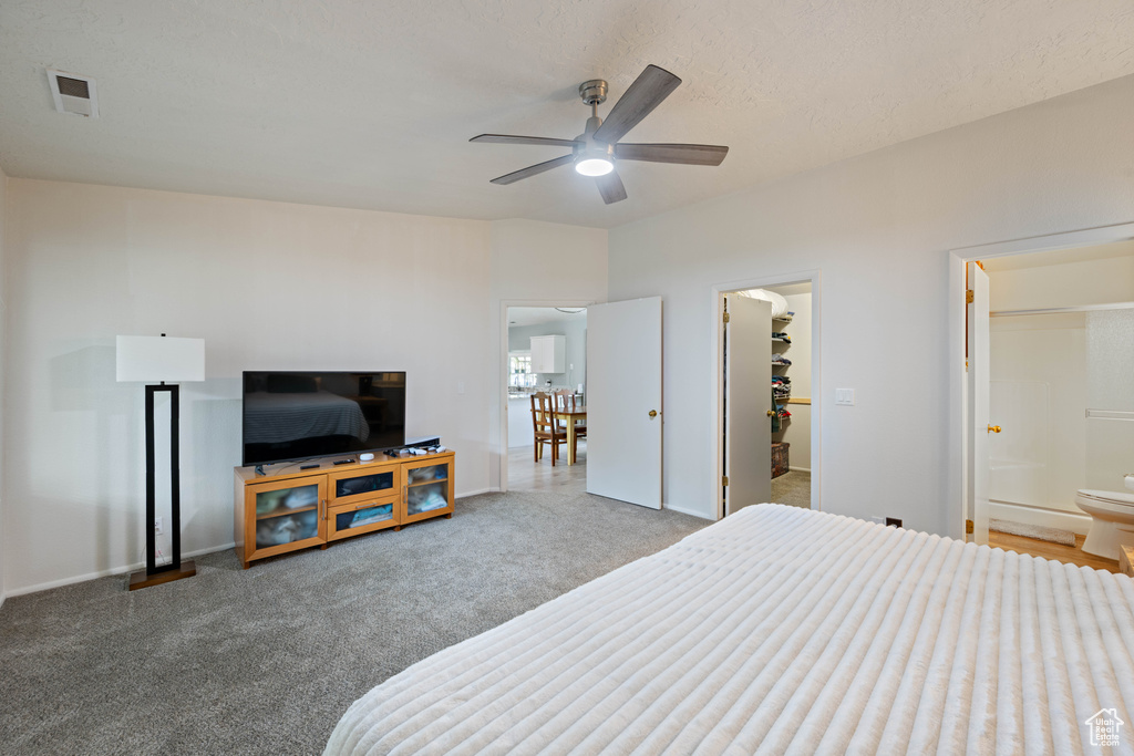 Bedroom featuring a ceiling fan, visible vents, a spacious closet, carpet flooring, and ensuite bath
