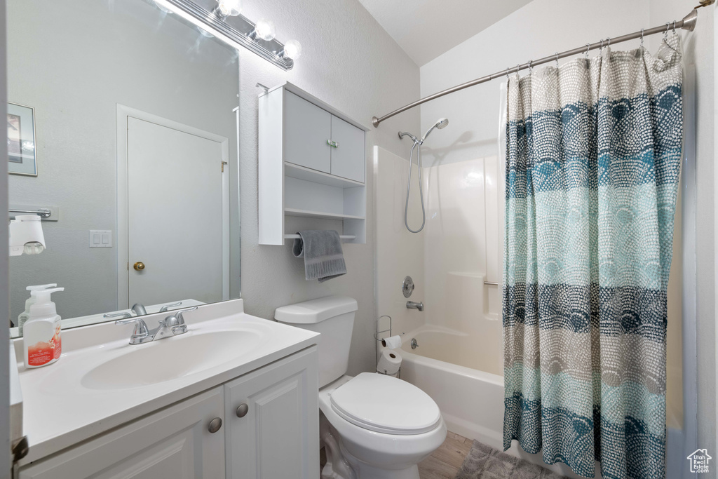 Bathroom featuring vanity, toilet, wood finished floors, and shower / tub combo