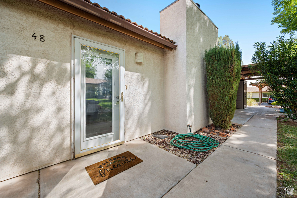 Doorway to property featuring a tiled roof and stucco siding