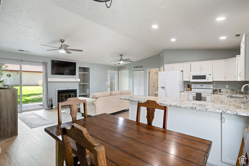 Dining area with a textured ceiling, ceiling fan, and visible vents