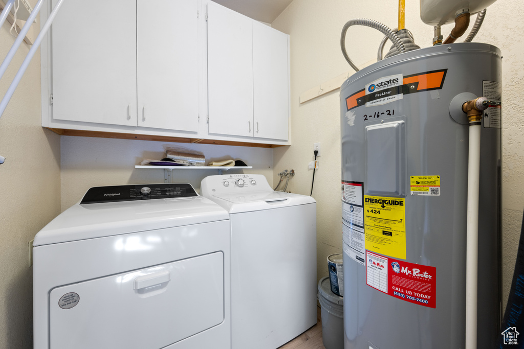 Clothes washing area with separate washer and dryer, cabinet space, and electric water heater