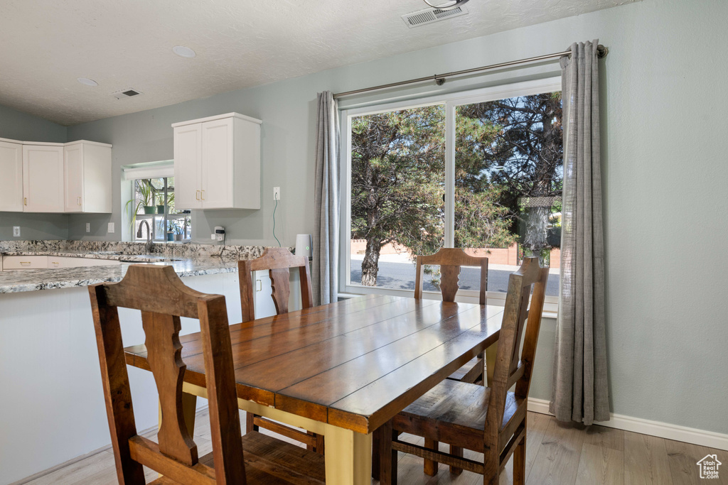Dining space with baseboards, visible vents, and light wood finished floors