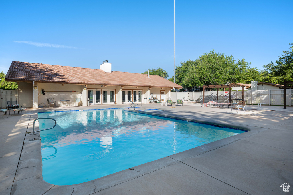 Community pool with french doors, fence, a pergola, and a patio area