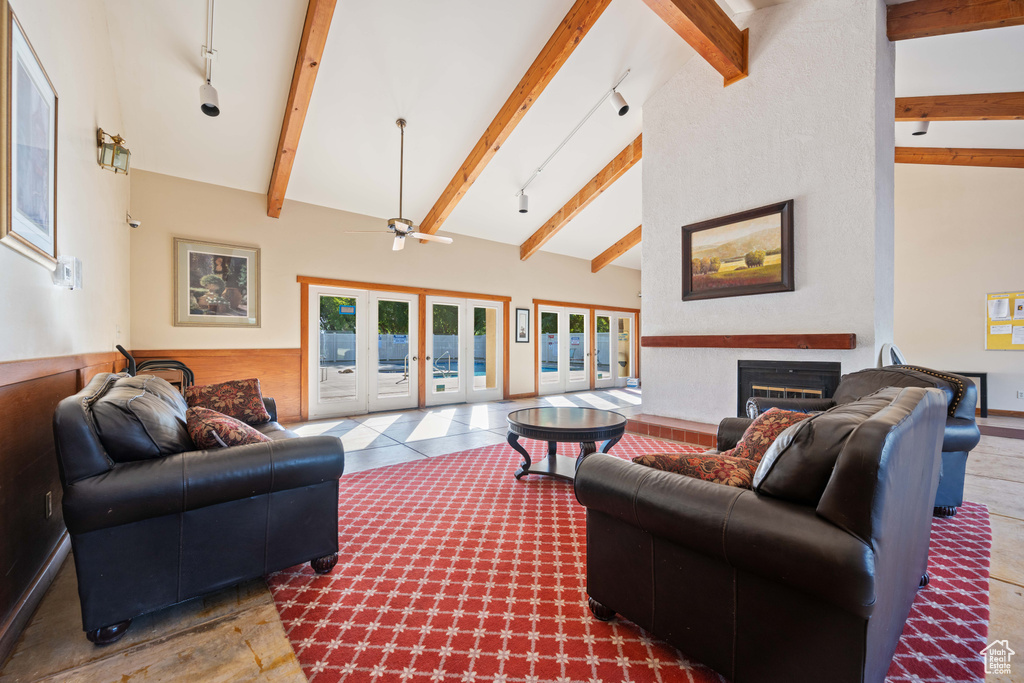 Living room featuring a glass covered fireplace, track lighting, french doors, and beam ceiling