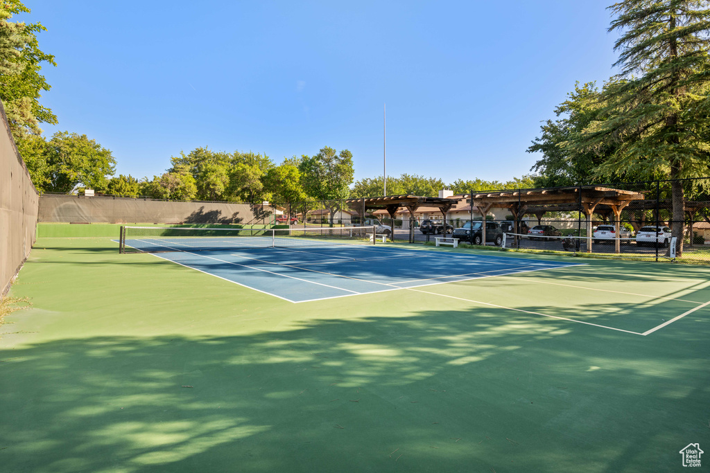 View of tennis court featuring community basketball court and fence