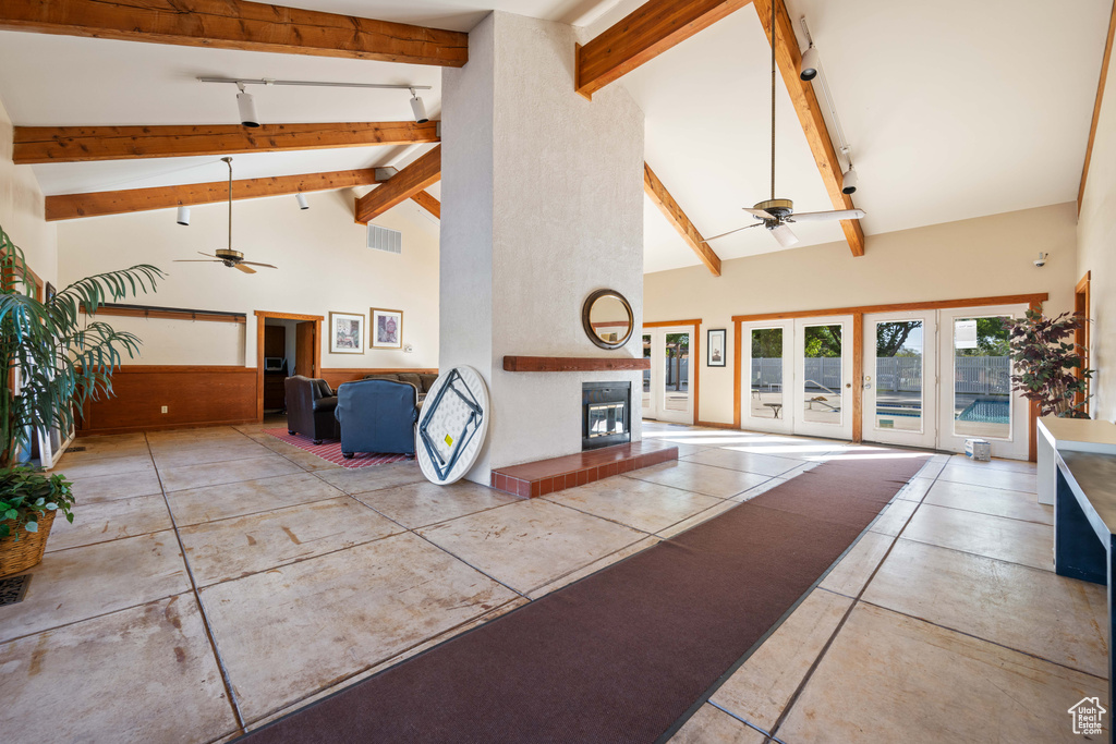 Living area with a glass covered fireplace, high vaulted ceiling, ceiling fan, and beamed ceiling