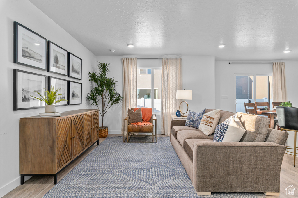 Living room with baseboards, recessed lighting, a textured ceiling, and light wood-style flooring