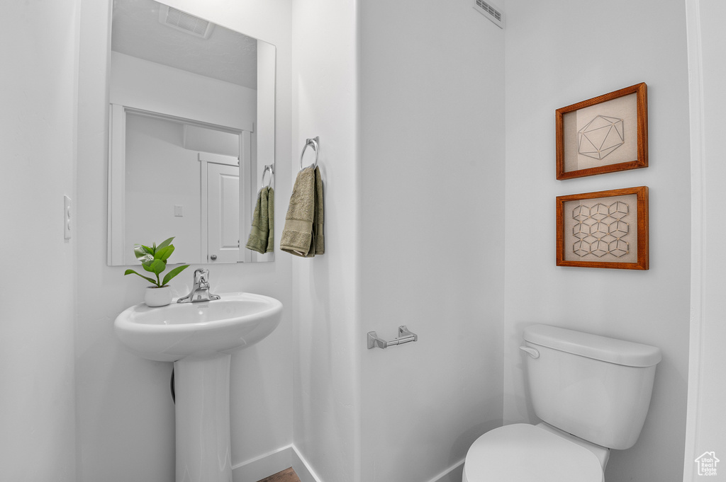 Half bath featuring a sink, baseboards, toilet, and visible vents